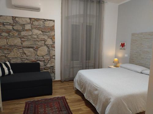 1 dormitorio con cama y pared de piedra en Glamour, en Viareggio