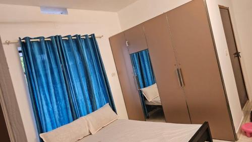 um quarto com cortinas azuis, um espelho e uma cama em Peaceful homes em Thrissur
