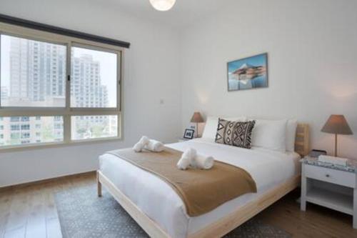 a white bedroom with a large bed and two windows at Unique 1Bedroom with Balcony Greens Dubai in Dubai