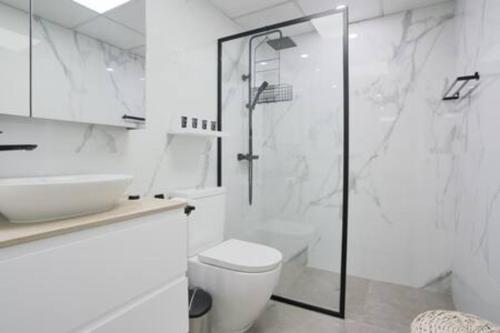 a white bathroom with a shower and a toilet at Unique 1Bedroom with Balcony Greens Dubai in Dubai