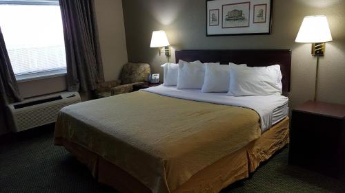 Habitación de hotel con cama grande con almohadas blancas en Gurnee Motel, en Gurnee