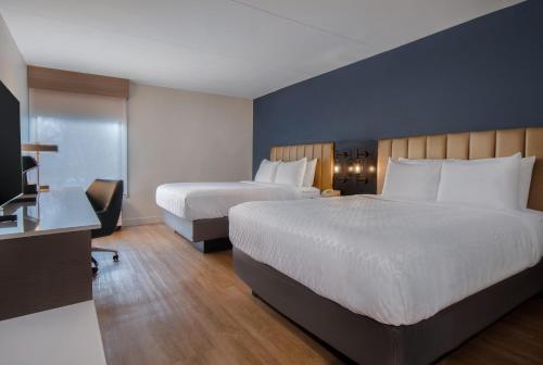 a hotel room with two beds and a flat screen tv at Best Western Plus Meadowlands in Secaucus