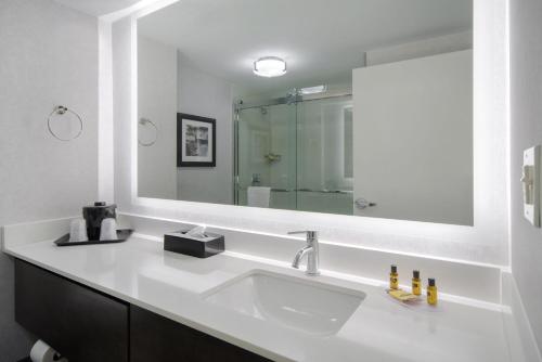 a bathroom with a sink and a large mirror at Best Western Plus Meadowlands in Secaucus