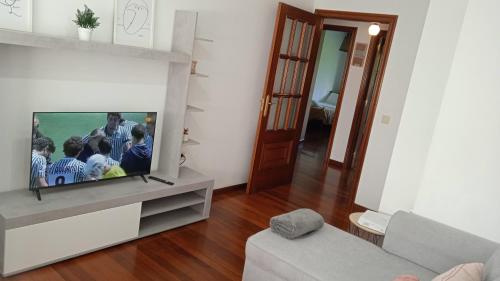sala de estar con TV y sofá en O Portiño de Sigueiro # a 10 min de Santiago, en Sigüeiro