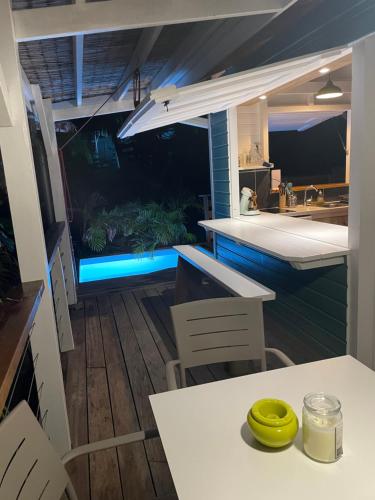 an outdoor kitchen and dining area with a table and chairs at Très joli bungalow et sa petite piscine privee in Rivière-Salée