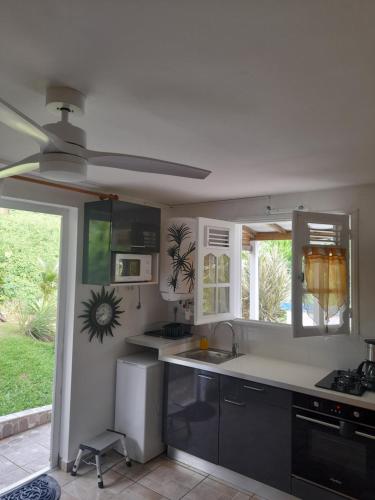 Il comprend une cuisine équipée d'un évier et d'un ventilateur de plafond. dans l'établissement Au petit salako, à Capesterre-Belle-Eau