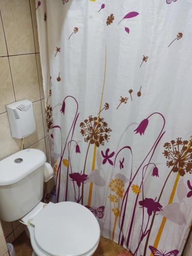 baño con aseo y cortina de ducha con flores en Hostal Saint Michell. El Quisco en El Quisco