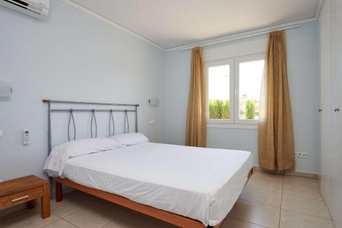 ein Schlafzimmer mit einem weißen Bett und einem Fenster in der Unterkunft Villa Cisne by Oliva Nova in Oliva