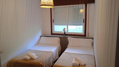 2 camas en una habitación con ventana en O Portiño de Sigueiro # a 10 min de Santiago, en Sigüeiro