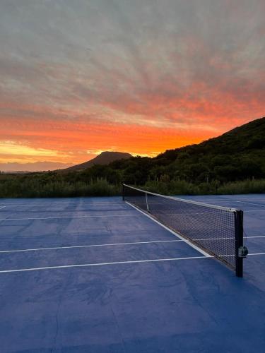 a tennis court with a net on it at sunset at Casa de campo altos de salamanca in Aiguá