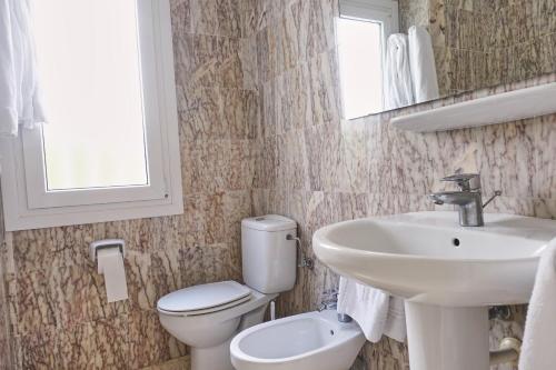 a bathroom with a sink and a toilet and a mirror at Peony by ON Travel in Oliva