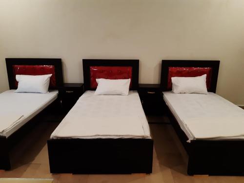 two twin beds in a room with red headboards at Regal Guest House in Bahawalpur