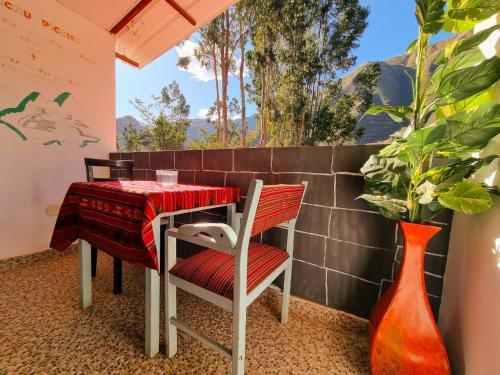 a table and chairs on a balcony with a table and vases at Valle verde, Hostel & camping in Urubamba