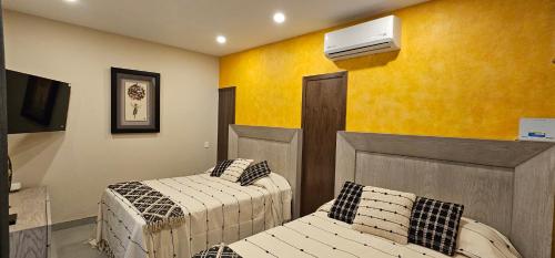 a room with two beds and a air conditioner on the wall at Real San Pedro. Hotel Boutique in San Pedro Tesistán