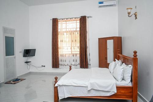 Schlafzimmer mit einem Bett mit weißer Bettwäsche und einem Fenster in der Unterkunft Tosh Home in Chukwani