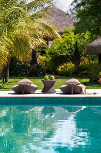 a swimming pool with two chairs and a bowl of fruit at Hotel Villa Balidendê in Barra Grande