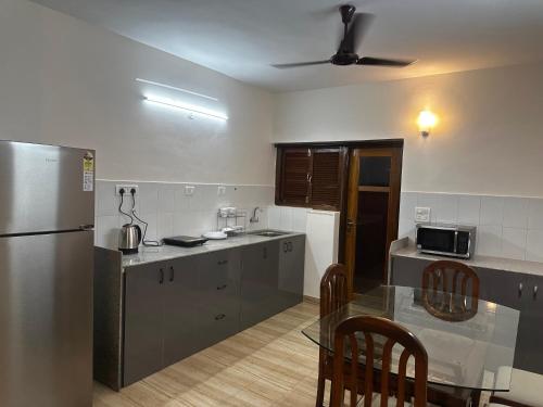 a kitchen with a table and a stainless steel refrigerator at Pixels Luxury Modern Apartment 5 Min to Palolem Beach in Canacona