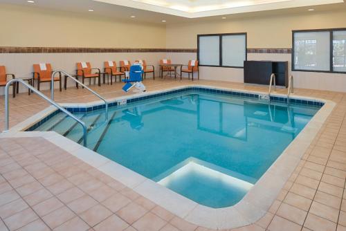 a pool in a hotel room with chairs and tables at Country Inn & Suites by Radisson, Brown Deer - Milwaukee North in Brown Deer
