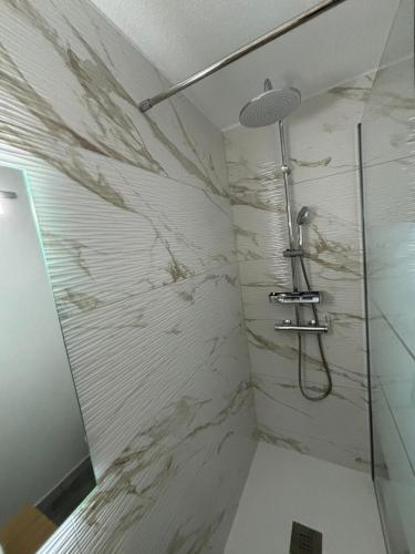 La salle de bains est pourvue d'une douche et d'un mur en marbre. dans l'établissement T2 rez de jardin direct plage, au Barcarès