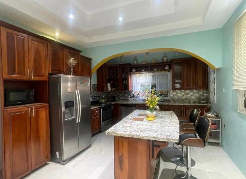 a kitchen with a stainless steel refrigerator and a counter at Cozy Elegance 3 Bedroom Estate in Portmore
