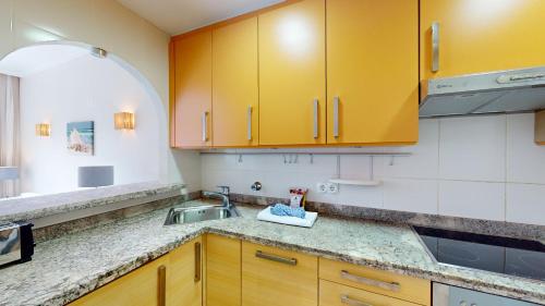 eine Küche mit gelben Schränken und einem Waschbecken in der Unterkunft Palmera by Oliva Nova in Oliva