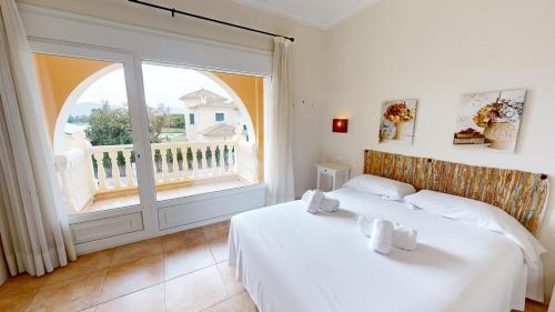 ein Schlafzimmer mit einem weißen Bett und einem großen Fenster in der Unterkunft Palmera by Oliva Nova in Oliva