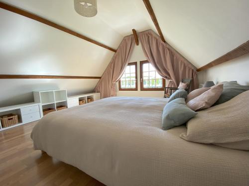 Un dormitorio con una cama grande con almohadas. en L'Etape Normande, en Sainte-Marguerite-des-Loges