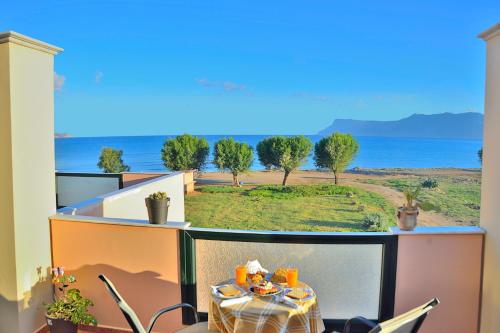 a table on a balcony with a view of the ocean at Girogiali Apts in Kissamos