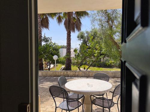 a patio with a table and chairs and a palm tree at La Maison One B&B in Carovigno