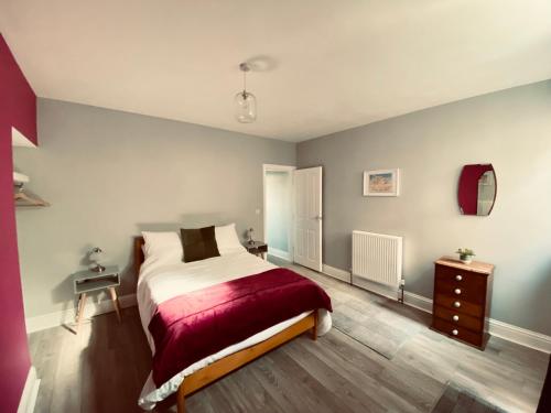 a bedroom with a bed with a red blanket at Tideway Apartment with Private Parking Space in Whitby