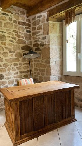 - un comptoir en bois dans une pièce dotée d'un mur en pierre dans l'établissement Authentique havre de Paix en Corrèze, à Darazac