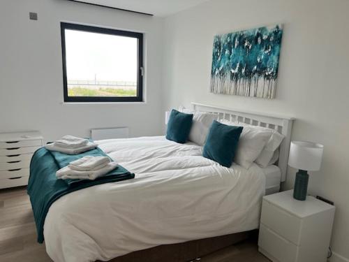 a bedroom with a large white bed with blue pillows at SoHot Stays Sail Apt Sea Views Ground Floor Free Parking in Ramsgate