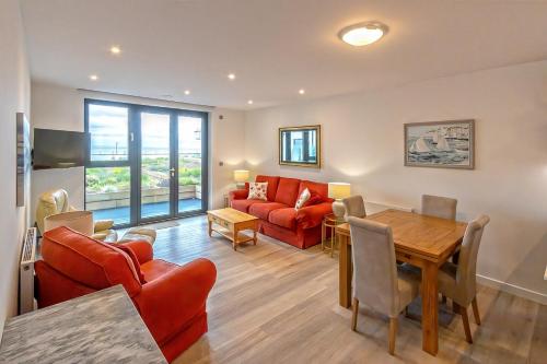 a living room with a red couch and a table at SoHot Stays Sail Apt Sea Views Ground Floor Free Parking in Ramsgate