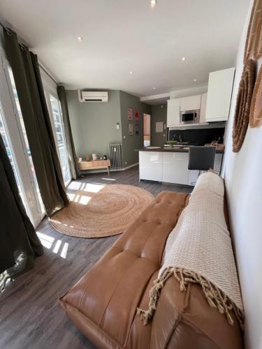 un salon avec un canapé marron et une cuisine dans l'établissement Appartement avec vue mer, à Nice