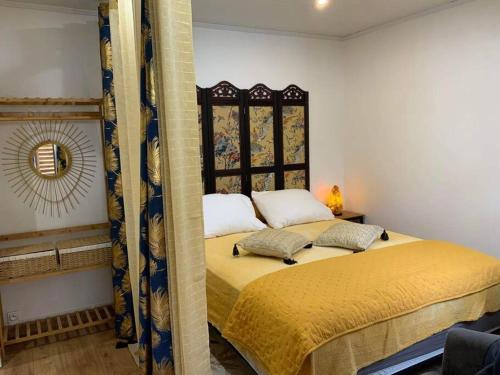 a bedroom with a bed with yellow sheets and pillows at La Monarette, l'oasis au fond d'un jardin in Sainte-Marie