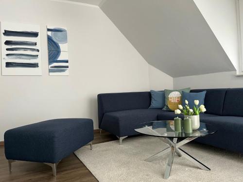 a living room with a blue couch and a glass table at Ferienwohnung "Delftbrise" Emden in Emden