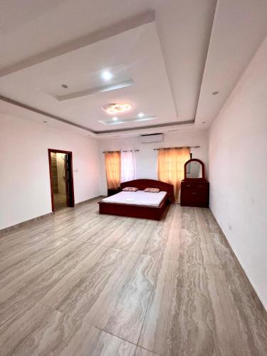 1 dormitorio con 1 cama y suelo de madera en Luxe Villa en Cotonú