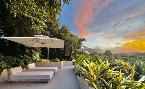 a patio with an umbrella and chairs and plants at KUNUK- Walk to Hermosa beach in Santa Teresa Beach