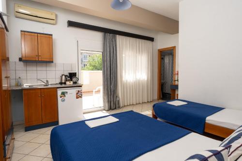 two beds in a room with a kitchen at Villa Zeus INN in Paralia Katerinis