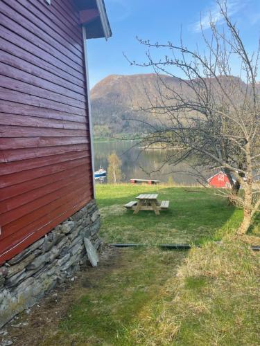 a picnic table next to a barn with a view of a lake at Krokenes in Sylte