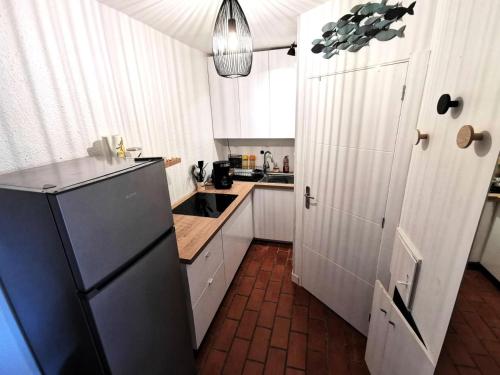 une cuisine avec des armoires blanches et un réfrigérateur noir dans l'établissement Résidence Maisons De La Mer 1 - Maisons & Villas pour 5 Personnes 691, à Leucate