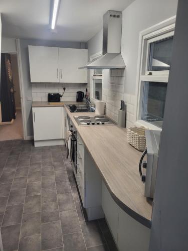 a kitchen with white cabinets and a wooden counter top at Cosy 2 Bedroom House in Kent