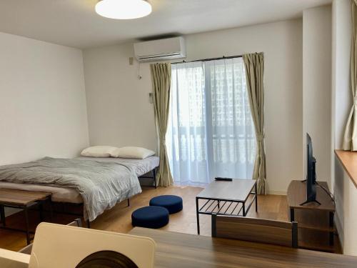 1 dormitorio con 1 cama, TV y mesa en GE Building AFUSO 2F - Vacation STAY 16648 en Atsutabaru