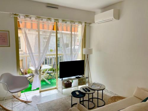 un salon avec un canapé, une télévision et une fenêtre dans l'établissement Lovely city center rental with balcony, à Beaulieu-sur-Mer
