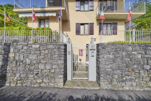 a stone wall with a gate in front of a building at B&B-FORESTERIA Casa Della Musica Lake Como in Mandello del Lario