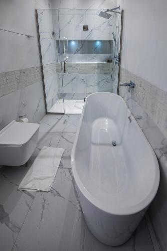 ein weißes Bad mit einer Badewanne und einem WC in der Unterkunft Treasurablehomes in Lagos