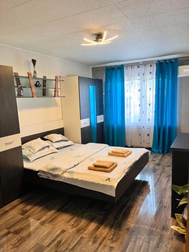 a bedroom with a large bed with blue curtains at Apartament Maria 1 in Băile Herculane
