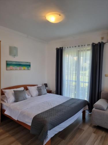 a bedroom with a bed and a chair and a window at Apartments Villa Marija in Petrovac na Moru