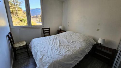 una camera da letto con un letto, due sedie e una finestra di Résidence Saint Genest - Appartement proche Village 4 pers MAE-1911 a Vallouise
