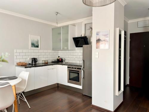 a kitchen with white cabinets and a stainless steel refrigerator at Apartament Gdynia Park 1 in Gdynia